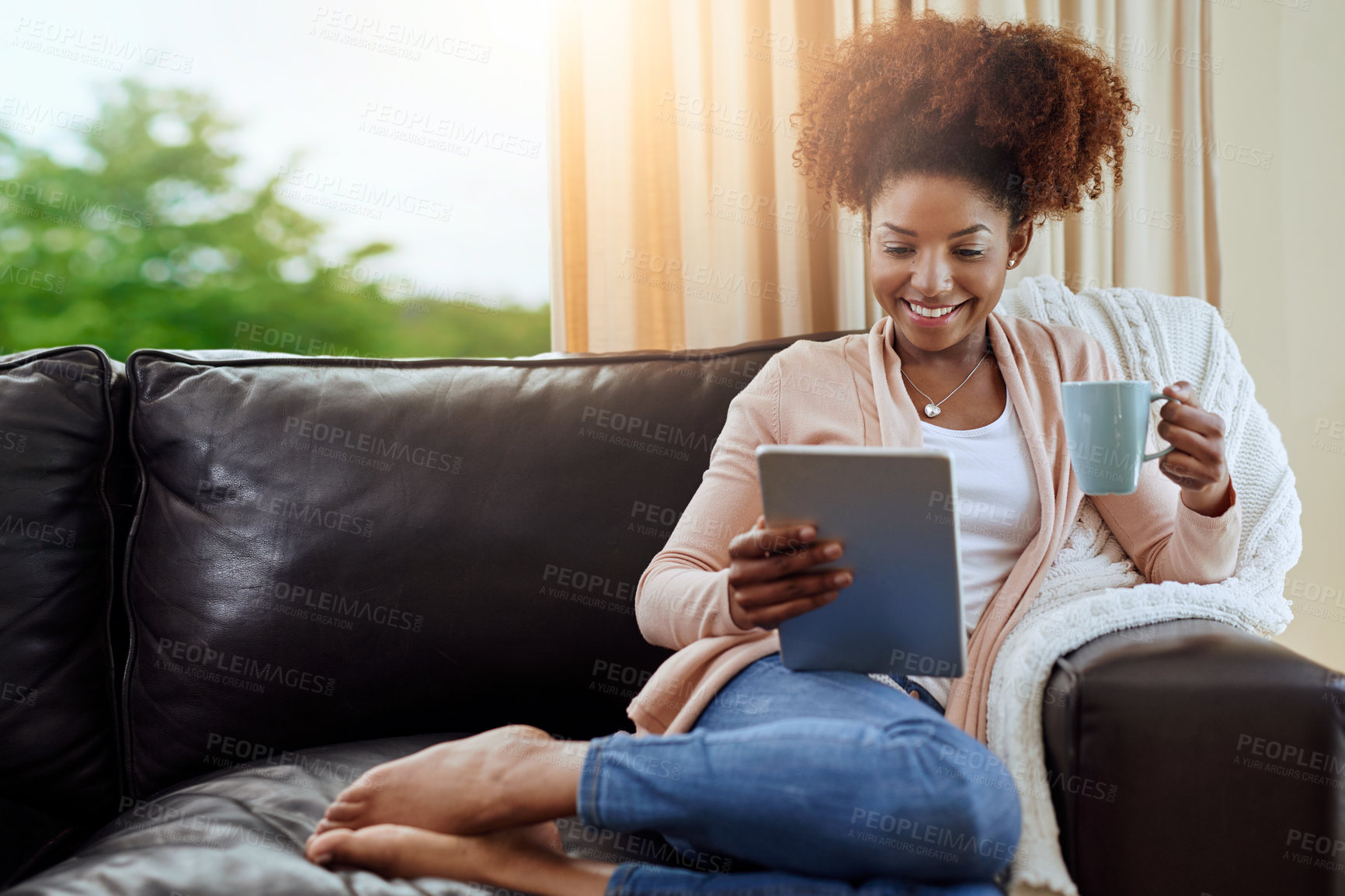 Buy stock photo Shot of a relaxed young woman using a digital tablet on the sofa at home