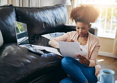 Buy stock photo Shot of a young woman going through her paperwork at home