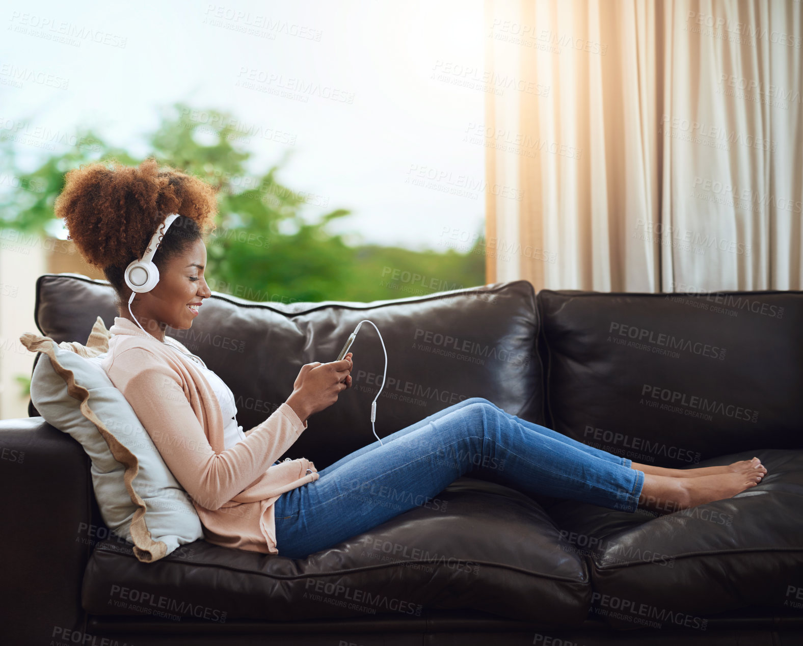 Buy stock photo Relax, phone and woman on sofa with headphones, smile and happy morning streaming in living room. Rest, wellness and girl on couch in home with music, mobile app and smartphone in calm apartment.