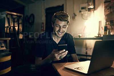 Buy stock photo Cropped shot of a handsome young man sending a text while working late in his office