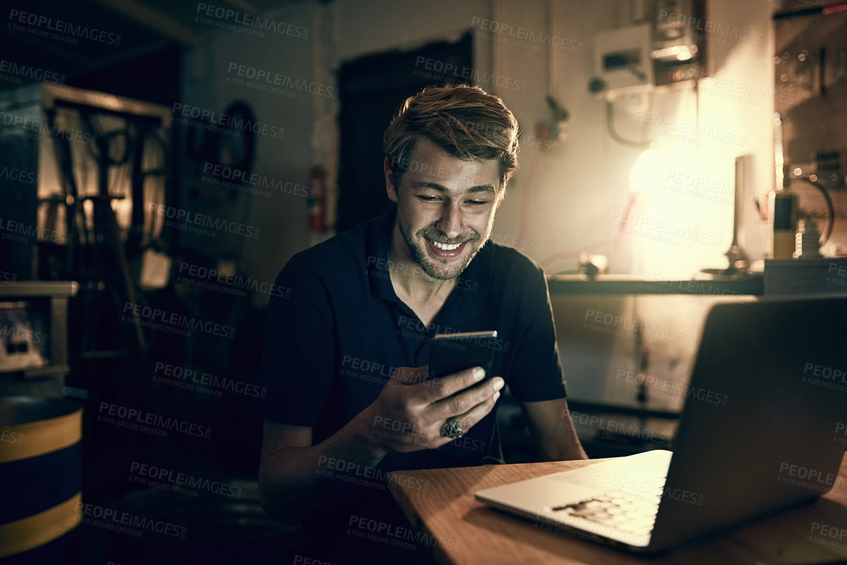 Buy stock photo Cropped shot of a handsome young man sending a text while working late in his office