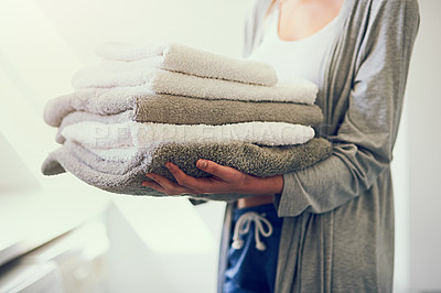 Buy stock photo Cropped shot of a young woman holding a pile of clean towels