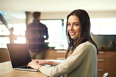 Buy stock photo Portrait of a young woman working on laptop with her boyfriend in the background at home