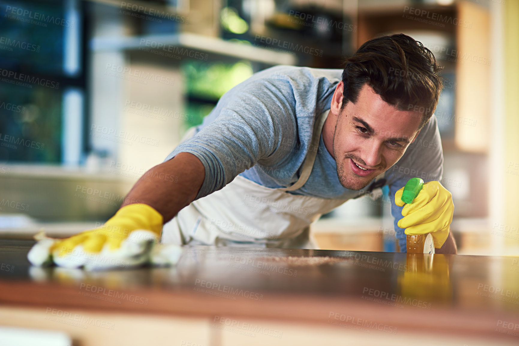 Buy stock photo Cropped shot of a young man cleaning a kitchen surface at home