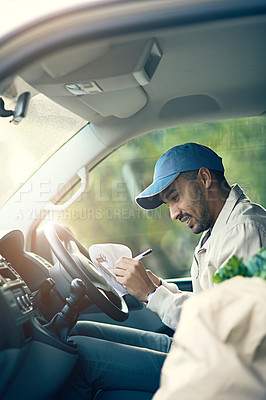Buy stock photo Cropped shot of a delivery man writing on a clipboard while sitting in his van