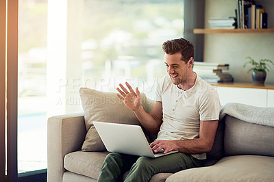 Buy stock photo Shot of a young man video chatting on his laptop at home