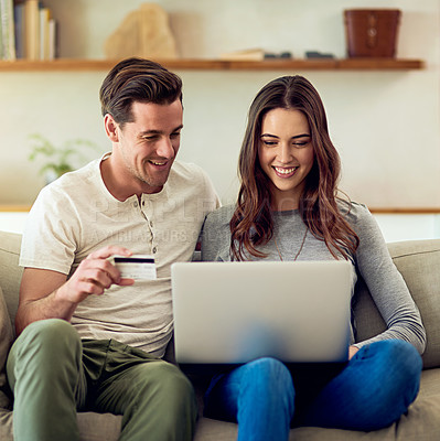 Buy stock photo Shot of a happy young couple making a credit card payment on a laptop together at home