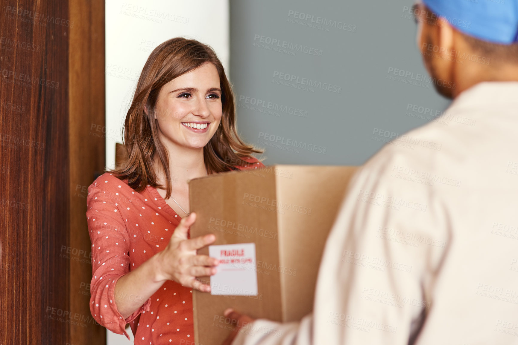 Buy stock photo Cropped shot of a young woman receiving her package from postal worker