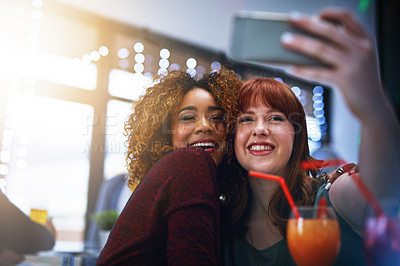 Buy stock photo Cropped shot of two young friends taking a selfie while having drinks at a party