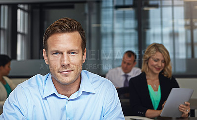 Buy stock photo Portrait of a businessman working at his desk with his colleagues in the background