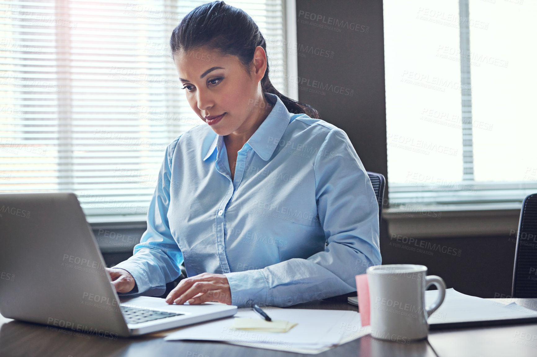 Buy stock photo Shot of a happy businesswoman using her laptop in the office