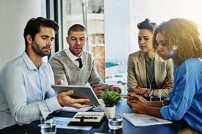 Buy stock photo Shot of a group of colleagues using a tablet while meeting in the boardroom