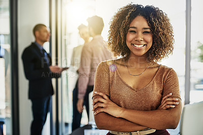 Buy stock photo Portrait of a businesswoman standing with her arms folded while some colleagues talk in the background