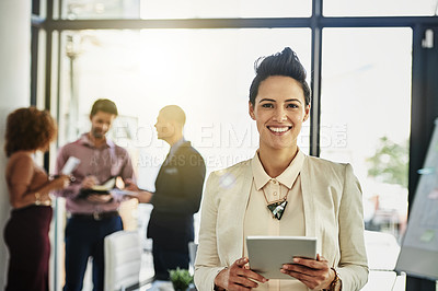 Buy stock photo Portrait of a businesswoman using her tablet while some colleagues talk in the background