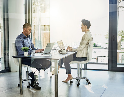 Buy stock photo Shot of two colleagues working in their office