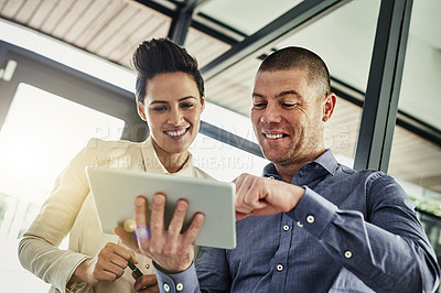 Buy stock photo Shot of two colleagues using a tablet while meeting in their office