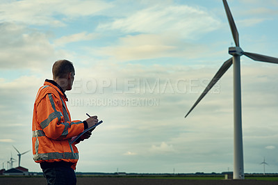 Buy stock photo Shot of a young engineer inspecting a wind turbine