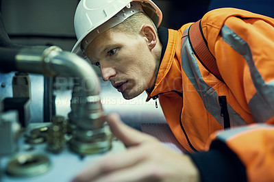 Buy stock photo Shot of a young engineer working with complicated machinery while wearing safety gear