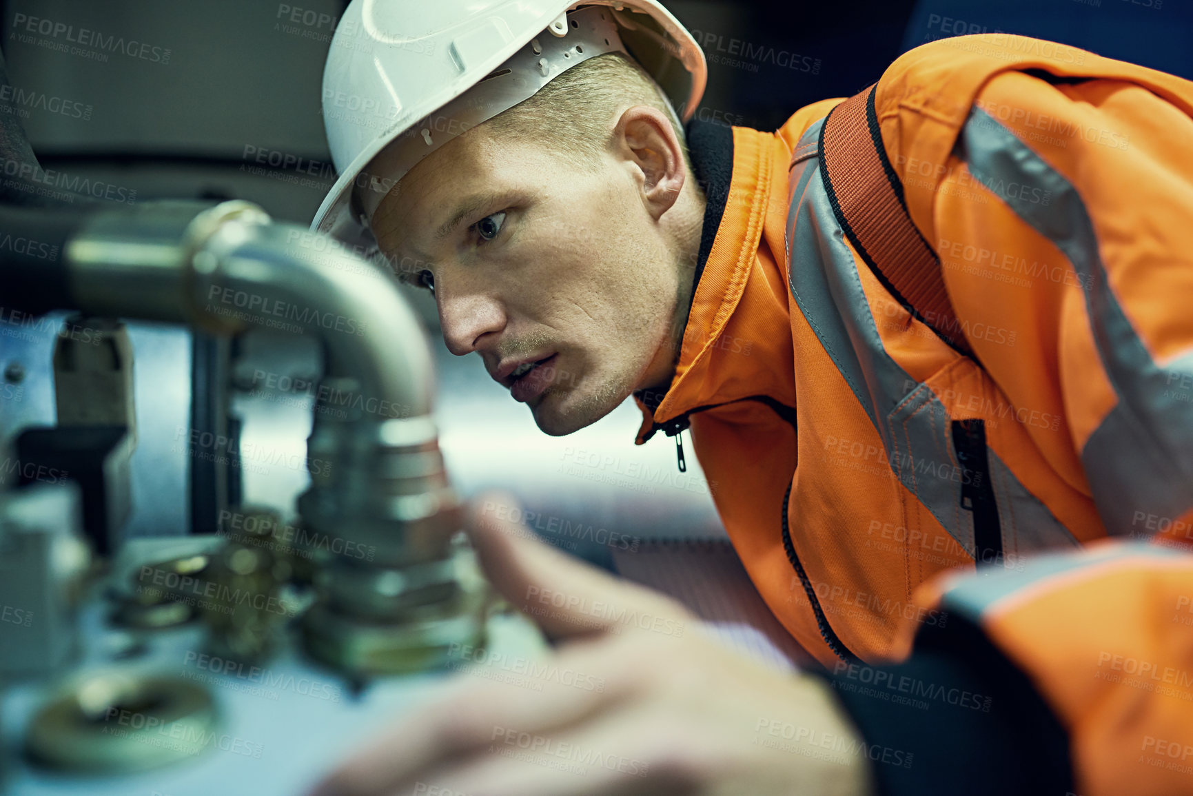 Buy stock photo Shot of a young engineer working with complicated machinery while wearing safety gear