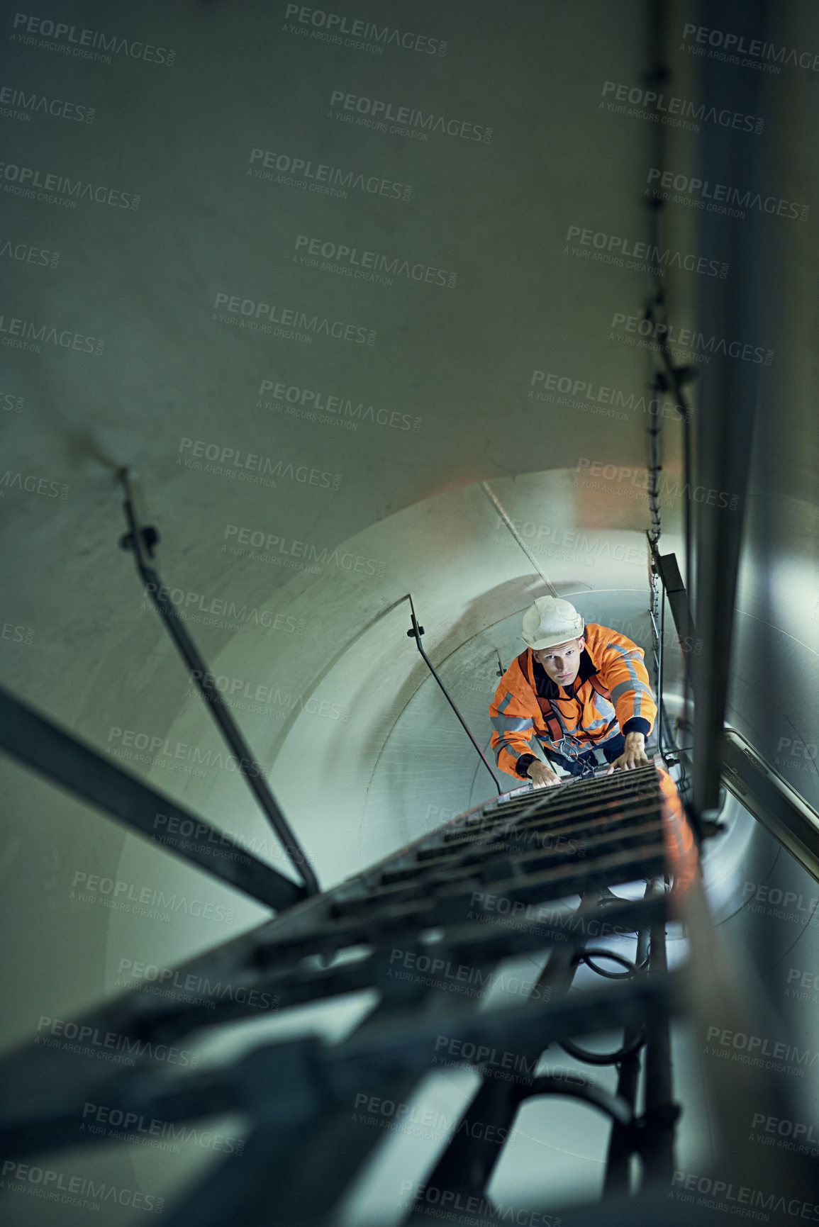 Buy stock photo Shot of a young engineer in safety gear climbing a ladder