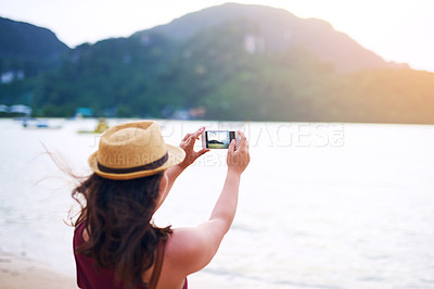 Buy stock photo Rearview shot of a young woman taking photographs at the beach