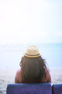 Buy stock photo Rearview shot of a young woman sitting on a chair at the beach