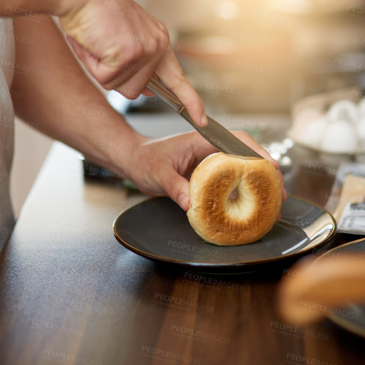 Buy stock photo Hands, knife and bread in kitchen for breakfast in home with diet, wellness and nutrition in morning. Person, meal prep and cutting bagel for food, natural protein and health for start at apartment