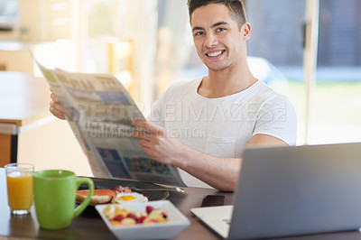 Buy stock photo Cropped shot of a young man reading the morning paper while having breakfast
