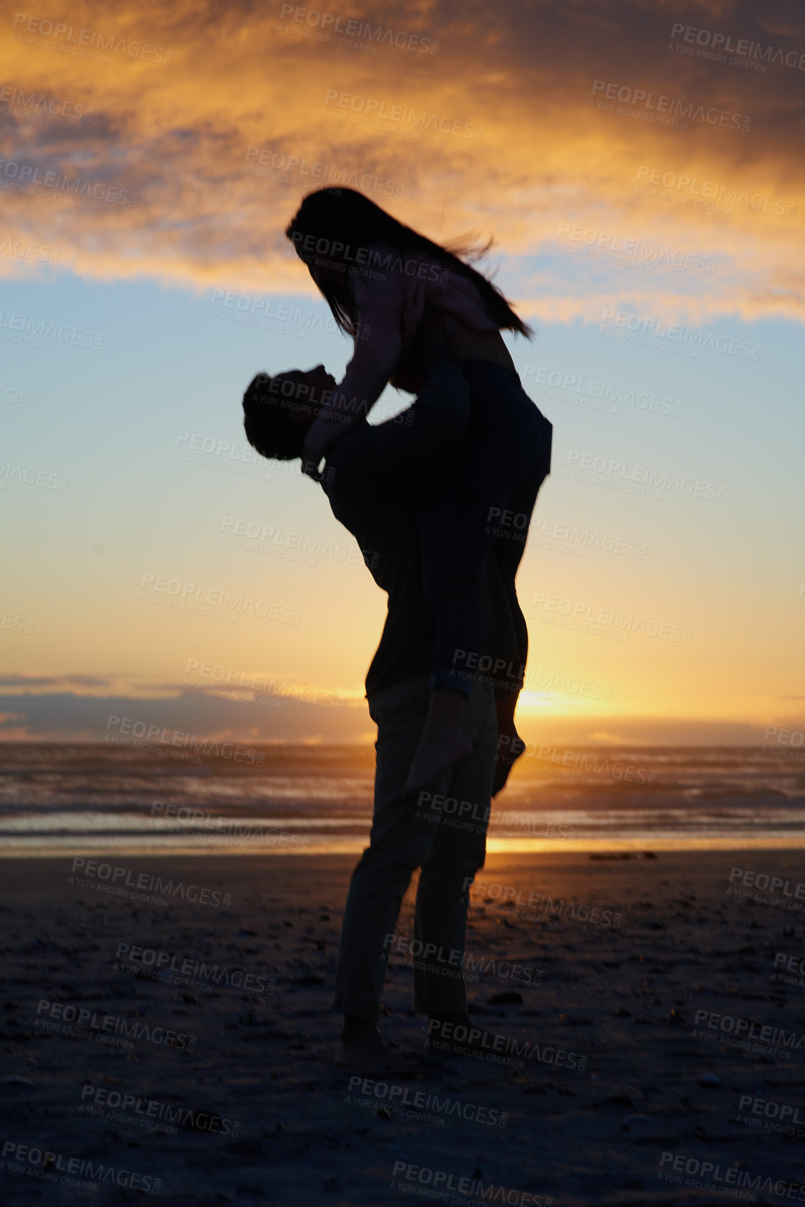 Buy stock photo Silhouette shot of a young couple on the beach