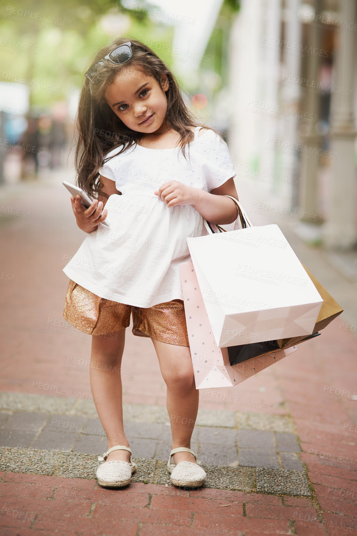 Buy stock photo Portrait of an adorable little girl holding shopping bags while out in the city