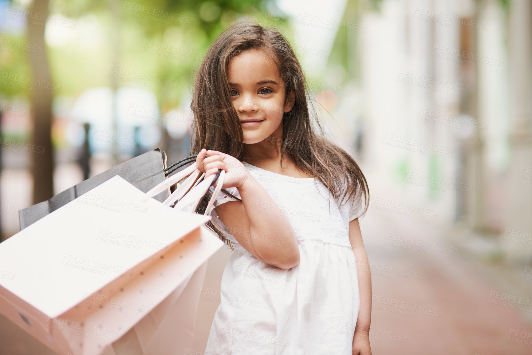 Buy stock photo Portrait of an adorable little girl holding shopping bags while out in the city