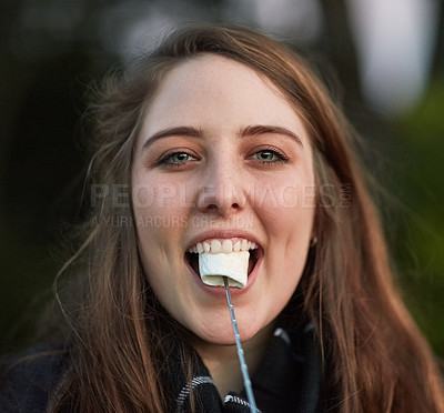 Buy stock photo Portrait of a pretty young woman eating a roasted marshmallow