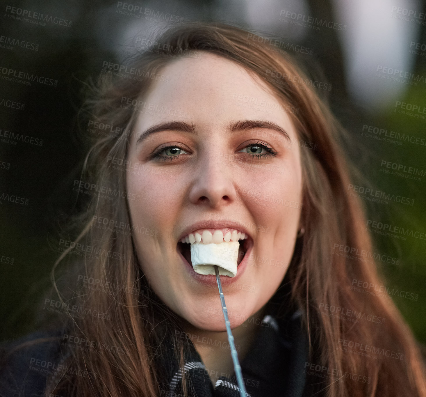 Buy stock photo Portrait of a pretty young woman eating a roasted marshmallow