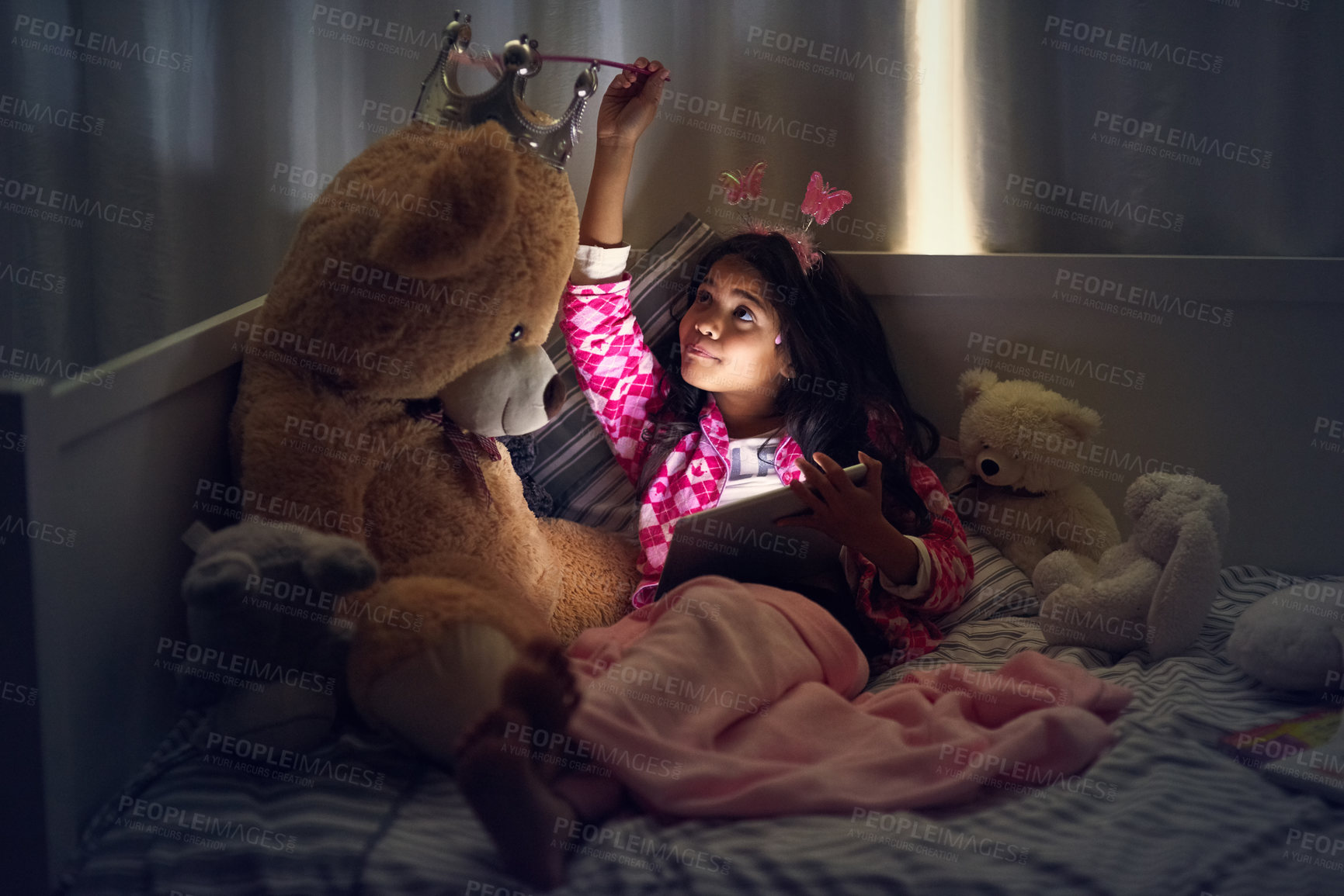 Buy stock photo Girl, teddy bear and tablet in bedroom at night for games, movies and online streaming. Technology, child and relax with toys in home for entertainment, video call and internet for communication app 