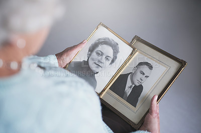Buy stock photo Cropped shot of a senior woman looking at old black and white photos of a man and a woman