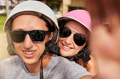Buy stock photo Shot of a young couple taking a selfie together while out for a ride on a scooter