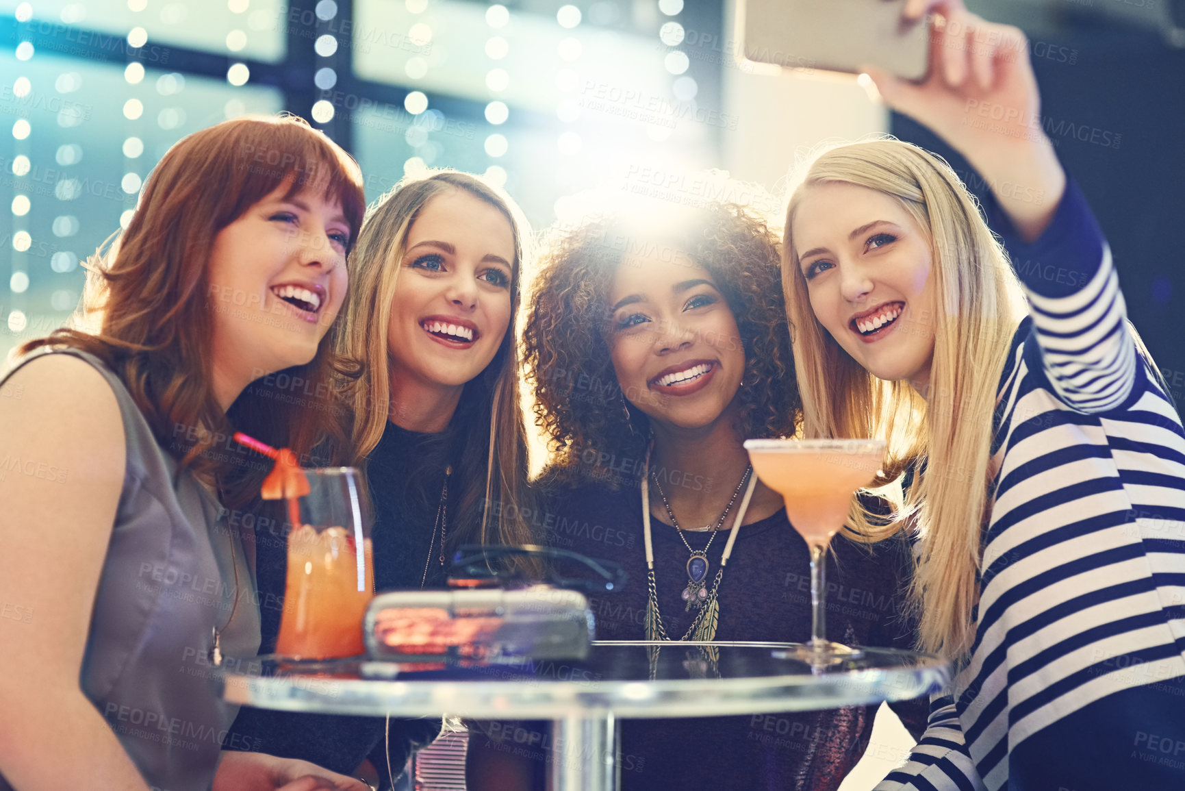 Buy stock photo Shot of a group of happy friends taking a selfie while enjoying cocktails
