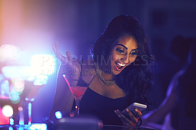 Buy stock photo Shot of a woman using her cellphone while sitting at a table in a nightclub