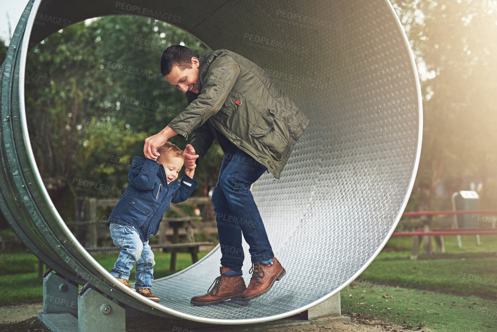 Buy stock photo Shot of a father and his little son playing together on a running wheel at the park