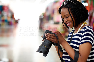Buy stock photo A young female tourist looking through her photographs while standing in a grocery store