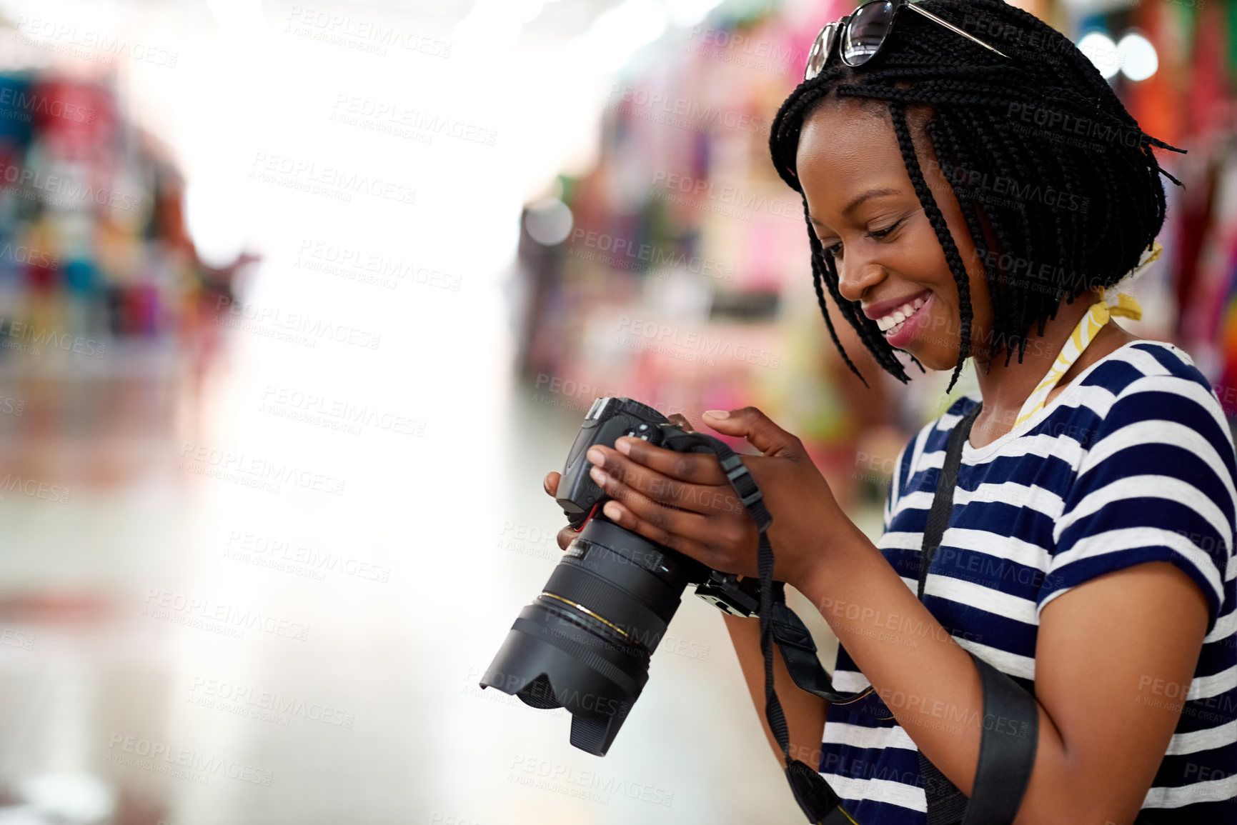 Buy stock photo A young female tourist looking through her photographs while standing in a grocery store