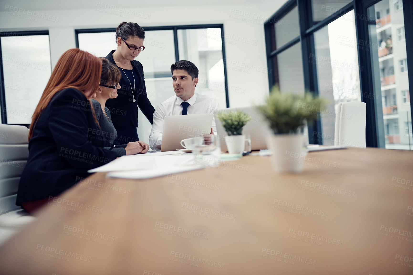 Buy stock photo Cropped shot of a group of businesspeople using a laptop together during a meeting in an office