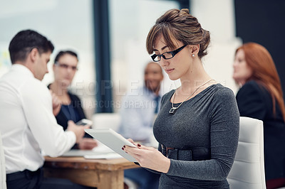 Buy stock photo Cropped shot of a businesswoman using a digital tablet during a meeting with her colleagues