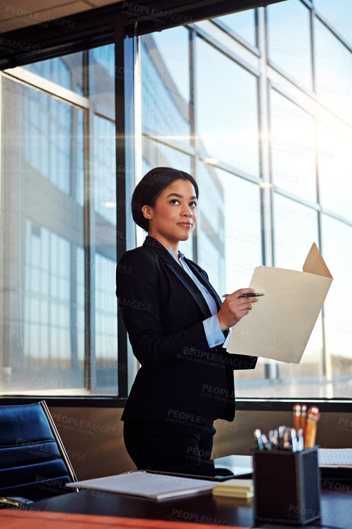 Buy stock photo Shot of a young female lawyer standing by her desk in the office