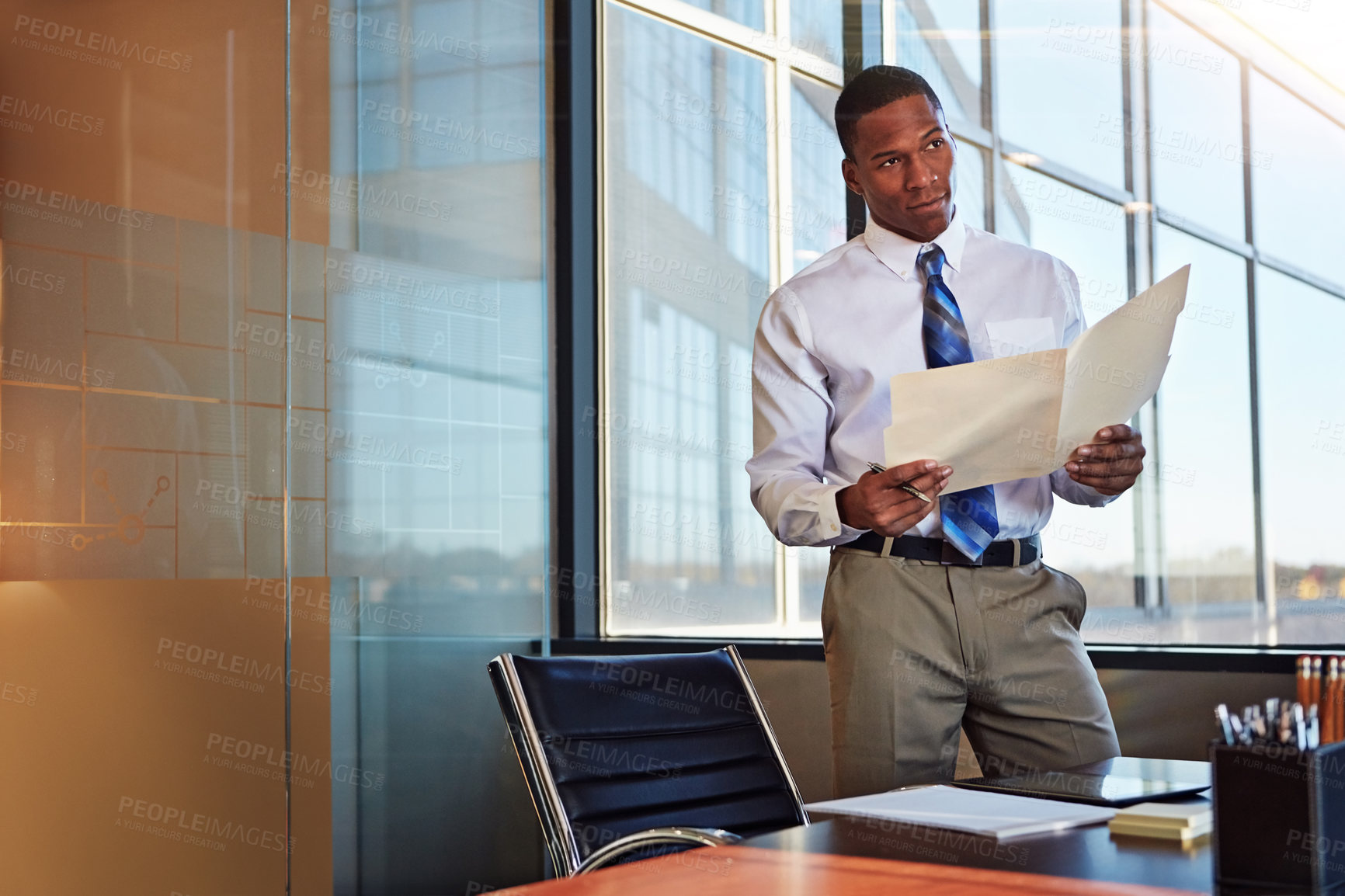 Buy stock photo Shot of a young male lawyer standing by his desk in the office