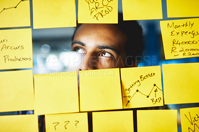 Buy stock photo Shot of a young man having a brainstorming session with sticky notes at work