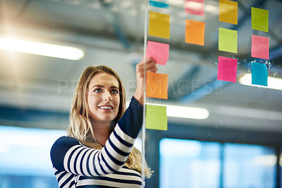Buy stock photo Shot of a young woman having a brainstorming session with sticky notes at work