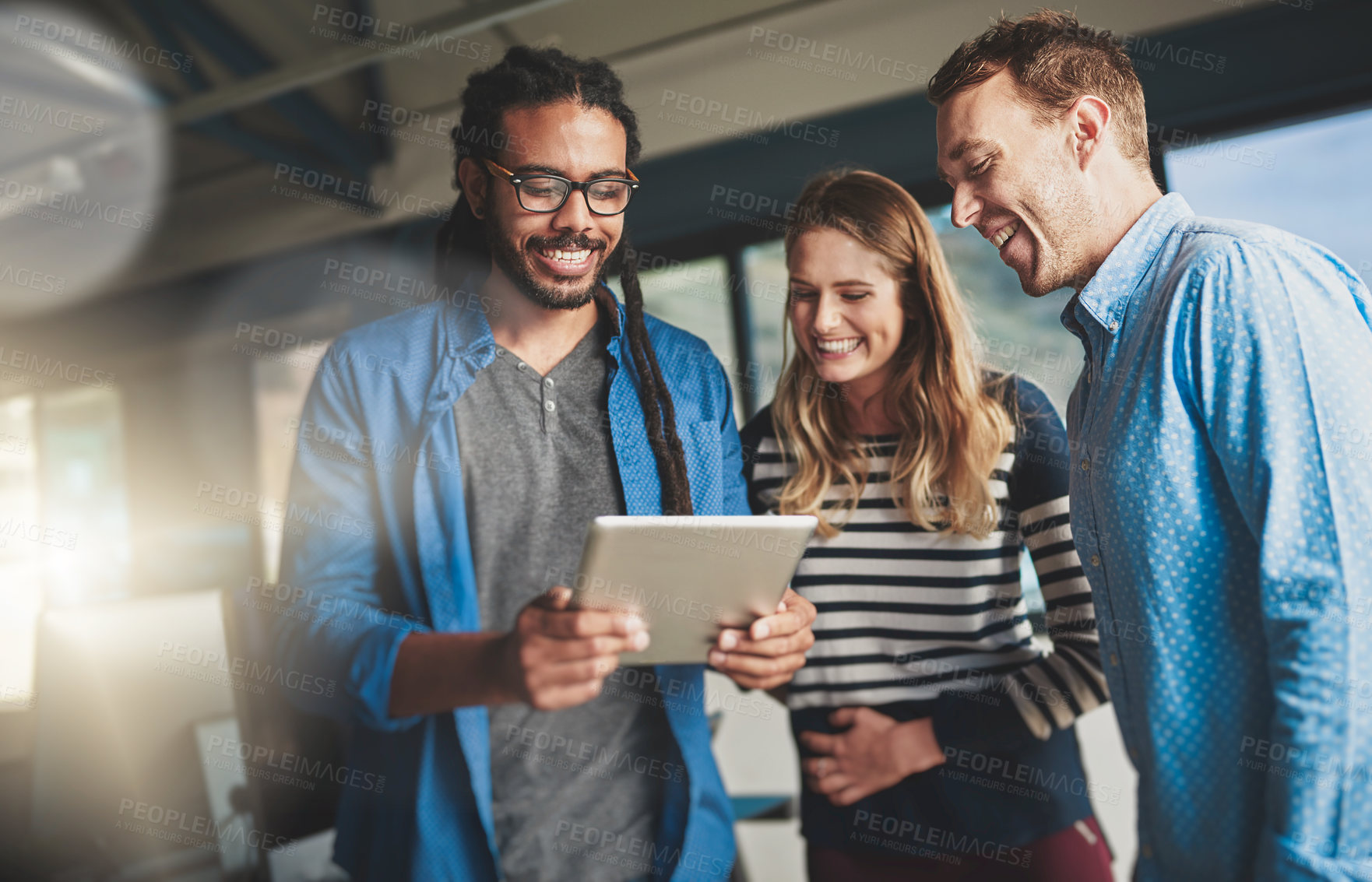 Buy stock photo Shot of three young designers talking over a digital tablet in their office