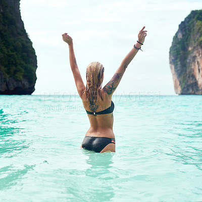 Buy stock photo Rear view shot of a beautiful young woman standing in the ocean