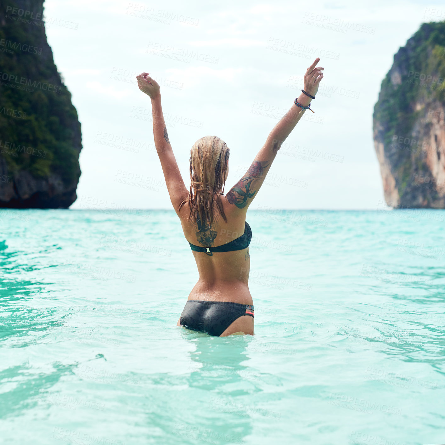 Buy stock photo Rear view shot of a beautiful young woman standing in the ocean